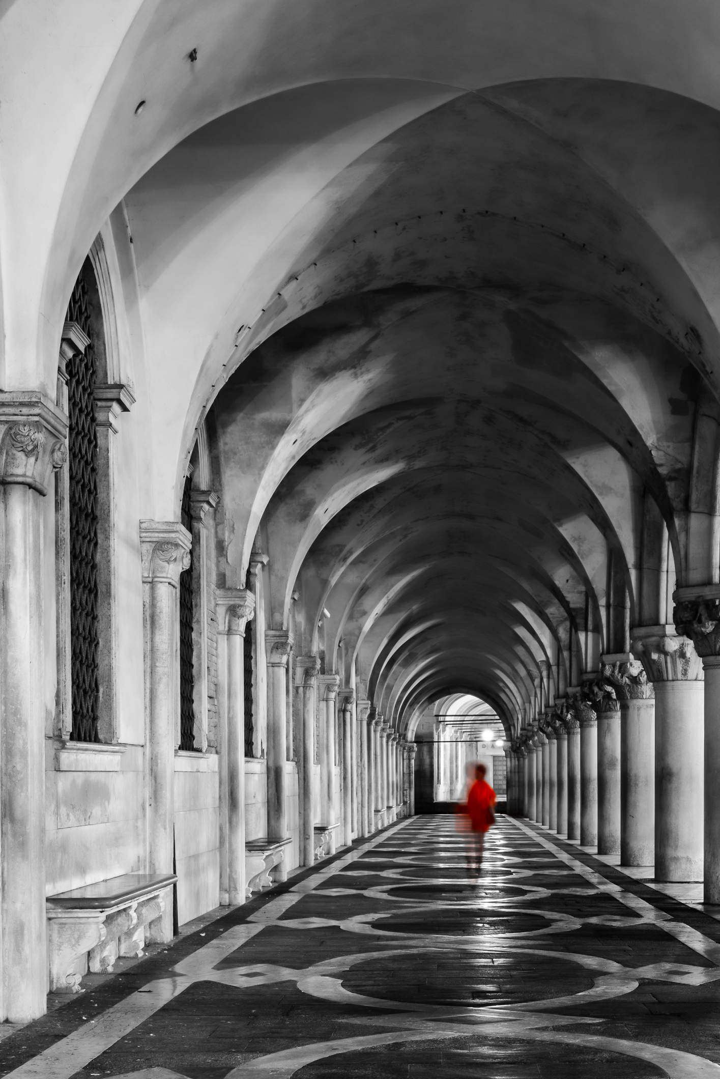 Klassisch historischer Säulengang am Dogenpalast mit gehender Frau im roten Mantel. Teilfarbe.