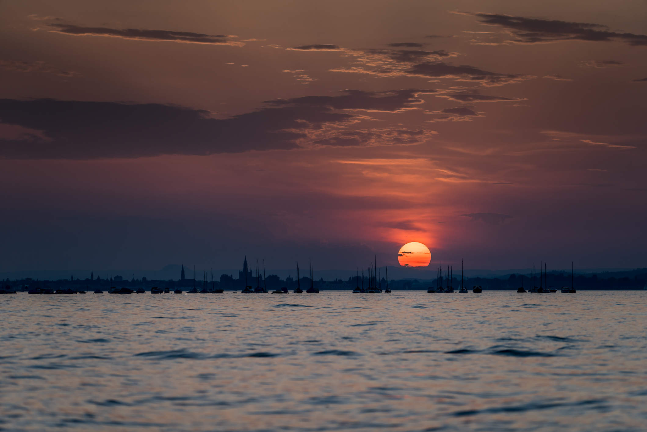 Silhouette von Konstanz und Segelbooten bei Sonnenuntergang