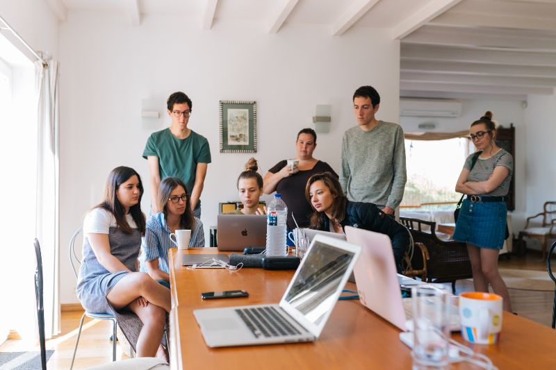 Eight people are intently looking at a computer screen