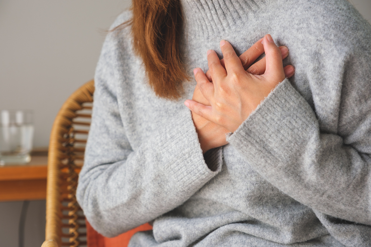 Brust-Schmerzen, Frau legt beide Hände auf den Herzbereich