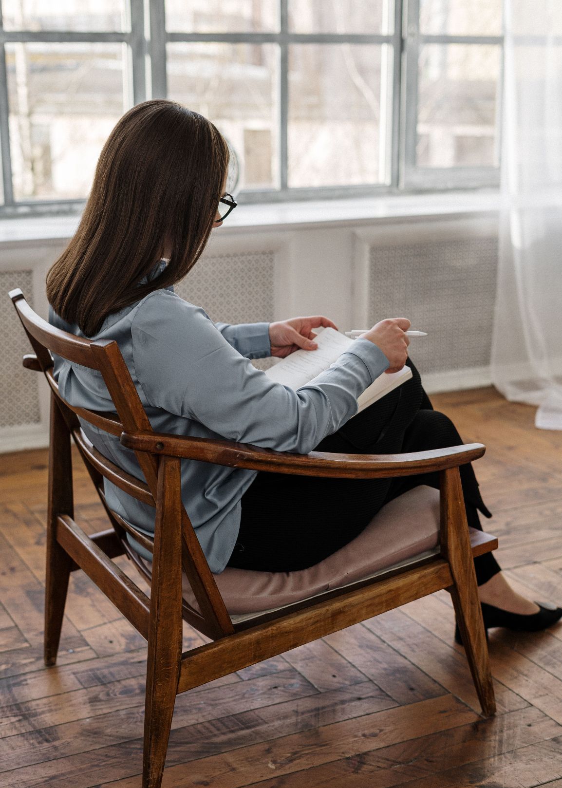 in einem schönen Holzstuhl sitzende Frau mit einem Schreibblock, die sich während eines wegorientierten Begleitungsgespräche Notizen macht.