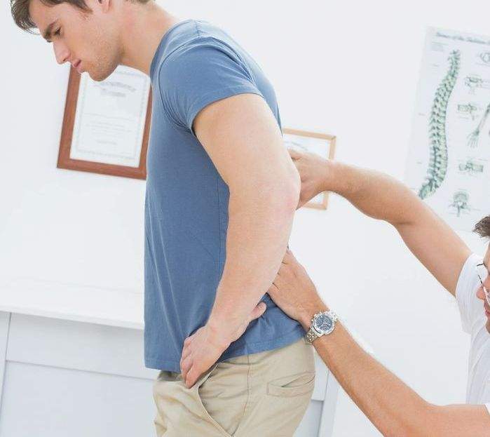 Therapeut palpiert den unteren Rücken einem Patienten mit Rückenschmerzen des unteren Rückens bei