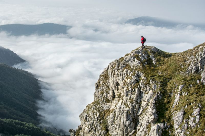 Person on mountain peak overlooking fog-covered valley