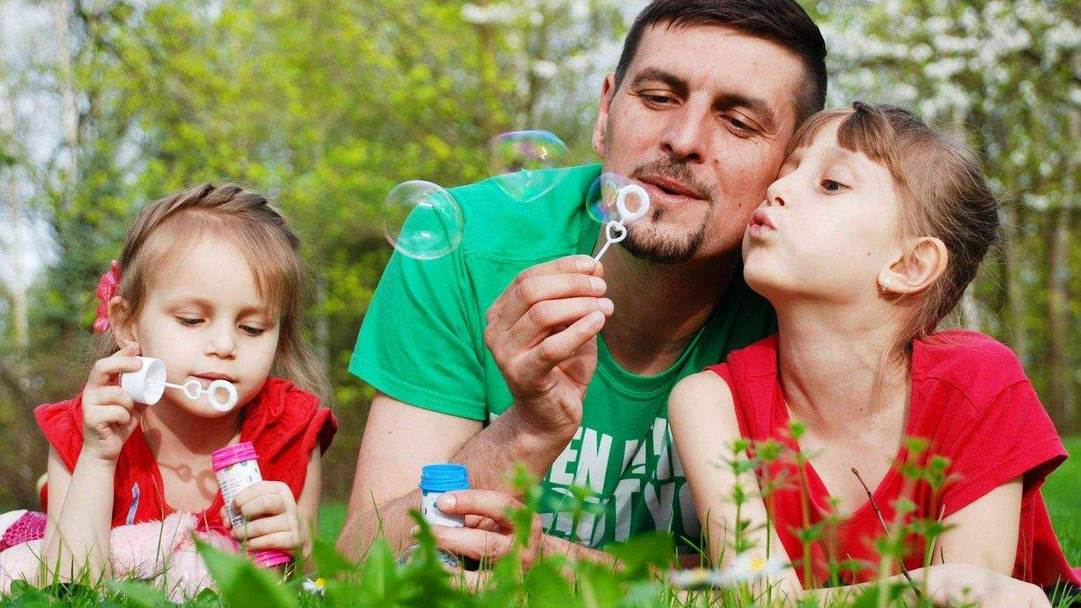 Vater mit den Töchtern im Gras und Seifenblasen