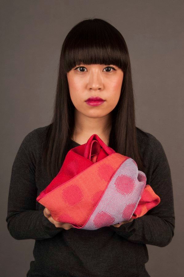 asiatische Frau hält Seidenschals in Pink mit Tupfen wie Geschenk