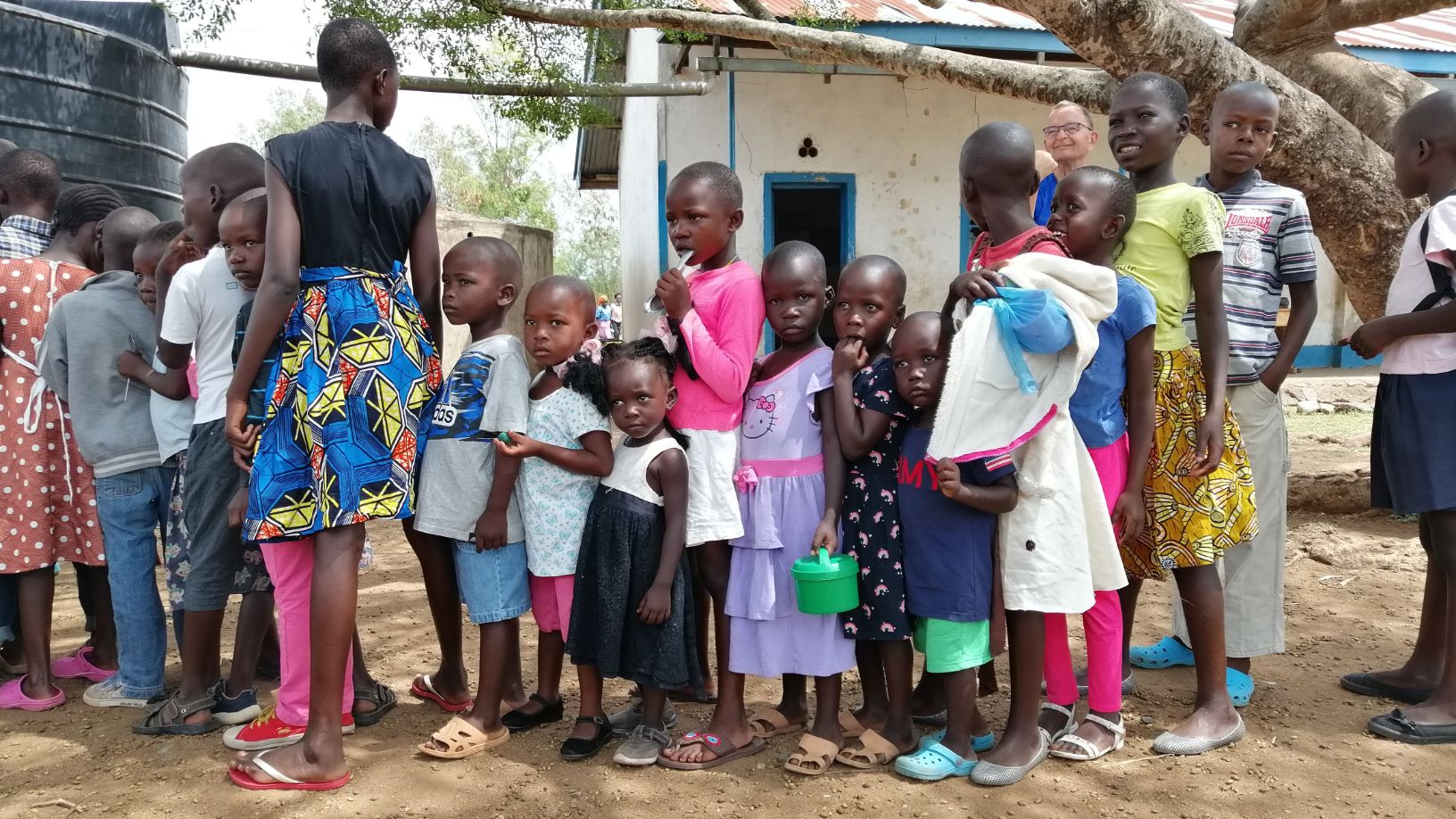 Afrikanische Kinder aus Kenia stehen in einer Schlange um eine Portion Essen zu erhalten