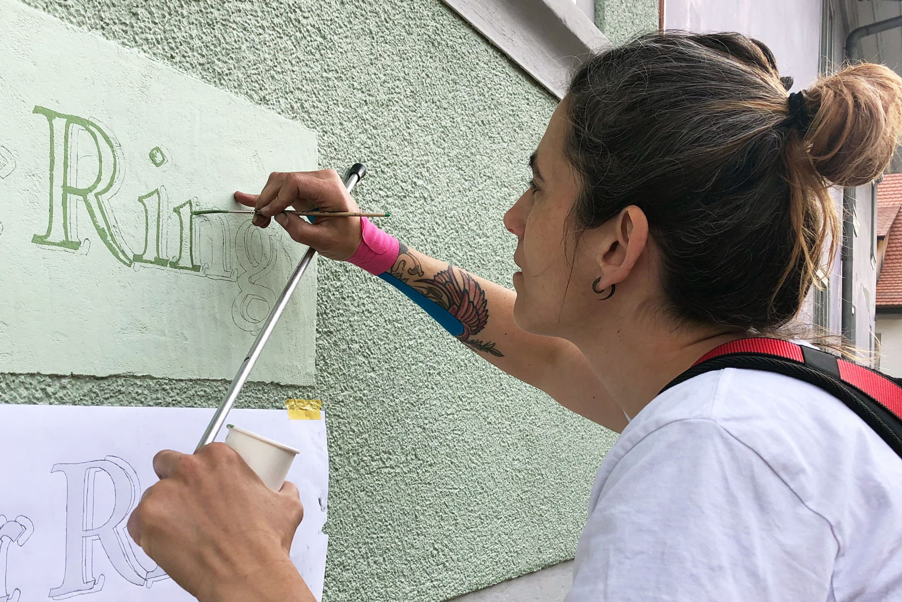 Traditionelle Schriftenmalerin am Malen eines Hausnamens auf eine Fassade