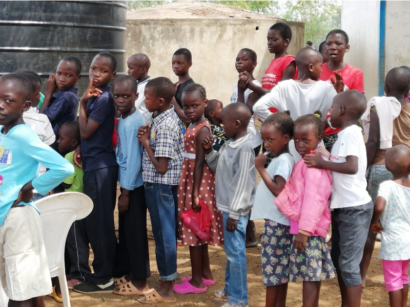 Afrikanische Kinder aus Kenia stehen in einer Schlange um eine Portion Essen zu erhalten